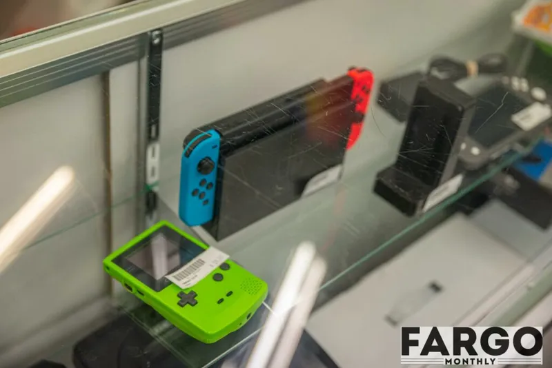 Lime-green Game Boy Color and Nintendo Switch on a glass store display shelf