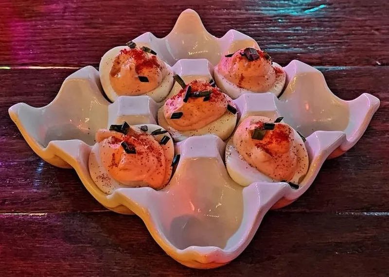 Six deviled eggs topped with paprika and herbs on a Texas-shaped ceramic tray