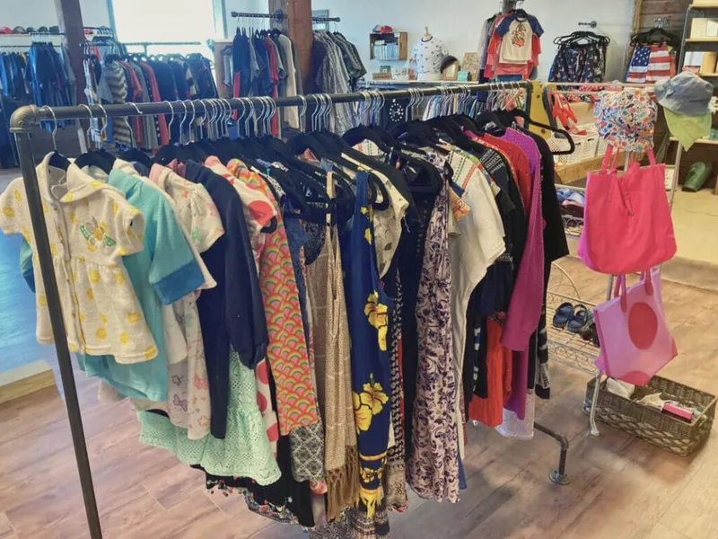 Colorful children's and women's clothing hanging on a rack inside a small boutique shop