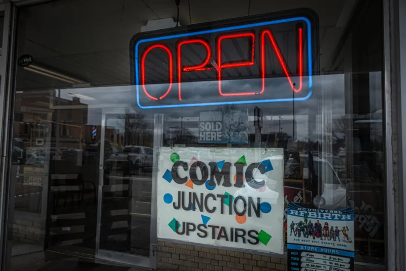 Neon 'Open' sign above a Comic Junction Upstairs storefront window