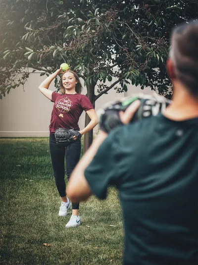 Young woman balancing a green apple on her head while being photographed outdoors