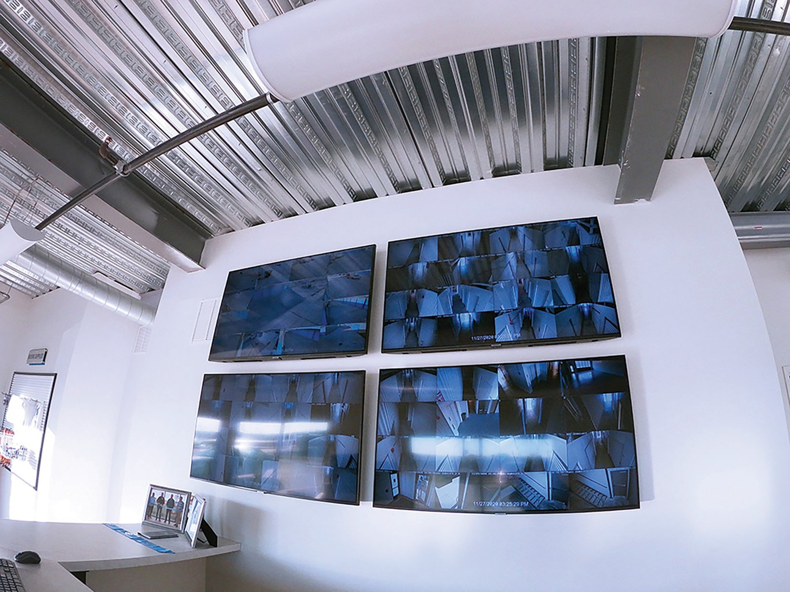 Four wall-mounted monitors showing security camera views