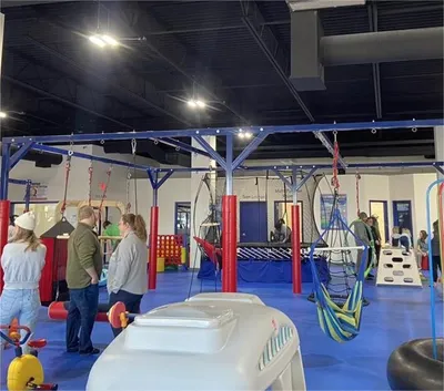 Indoor play facility with blue metal frame structures, swings, and trampolines