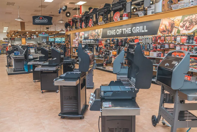 Retail store floor displaying rows of black grills beneath a 'King of the Grill' sign