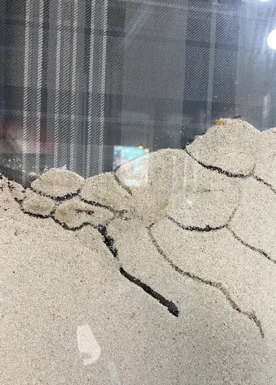 Sand sculpted into an organic cracked-earth pattern against a glass surface