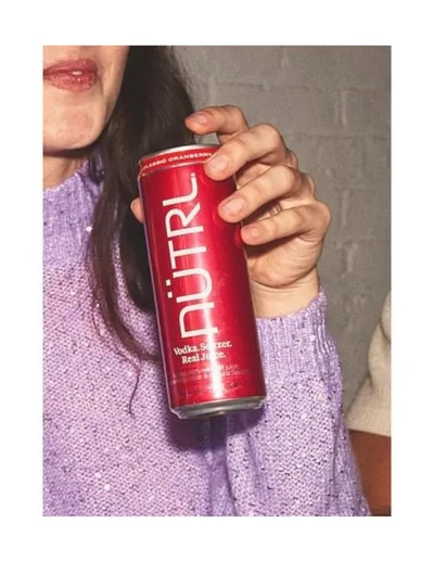 Person in a lavender sweater holding a red NÜTRL Vodka Seltzer can