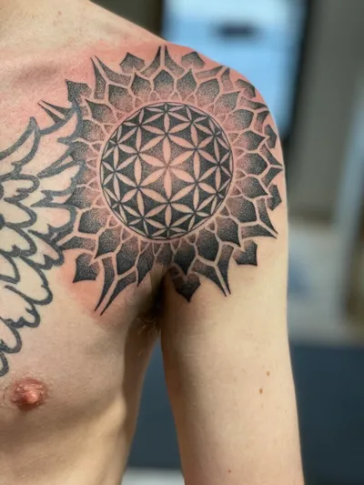 Geometric mandala and flower of life tattoo on a person's shoulder