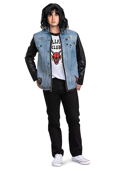 Person in denim vest, graphic club tee, black leather sleeves, and curly black wig