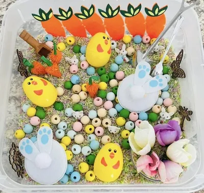 Easter sensory bin with chick figurines, pastel beads, carrot decorations, and bunny picks