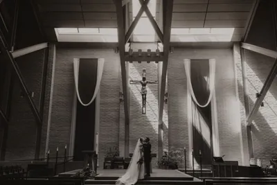 Bride and groom share a kiss at a church altar beneath a large crucifix