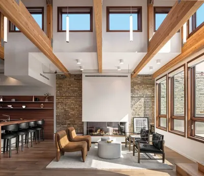 Airy living room with exposed brick fireplace, wood beams, and double-height ceilings