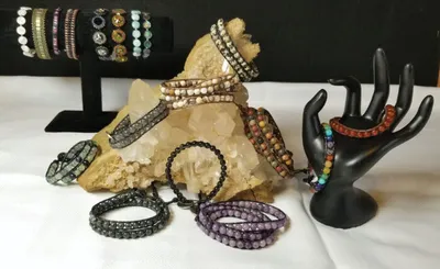 Assorted beaded and stone bracelets displayed on black jewelry stands and a crystal rock