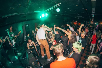 Energetic punk concert crowd packed into a small dimly lit venue with green stage lighting