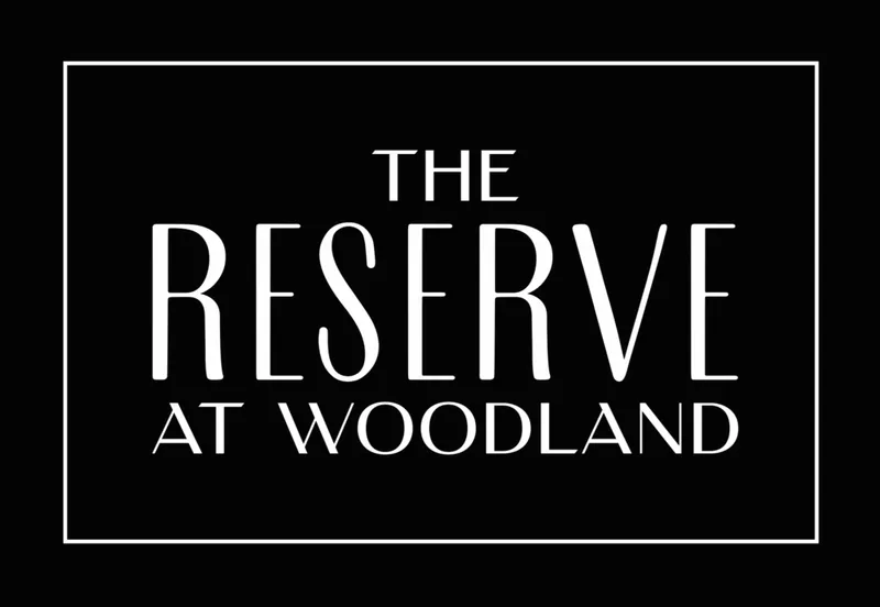 The Reserve at Woodland logo in white text on a black background