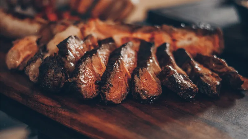 Sliced grilled steak fanned out on a wooden cutting board
