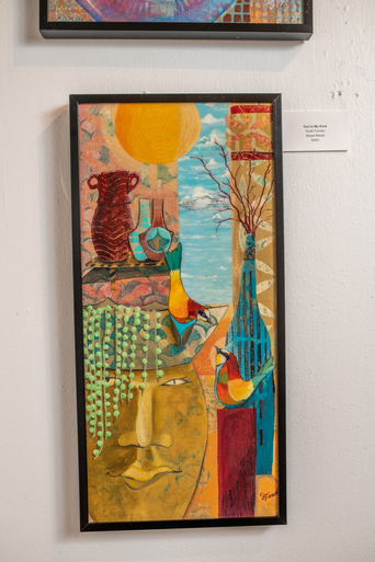 Framed mixed-media painting with colorful birds, vases, a sun, and a large face amid bold hues