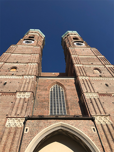 Twin brick towers of a Gothic cathedral seen from below against a deep blue sky