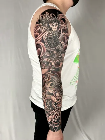 Black and grey Japanese-style full sleeve tattoo featuring a monkey warrior figure