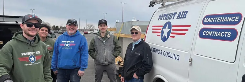 Five Patriot Air Heating & Cooling crew members posing beside a branded white work van