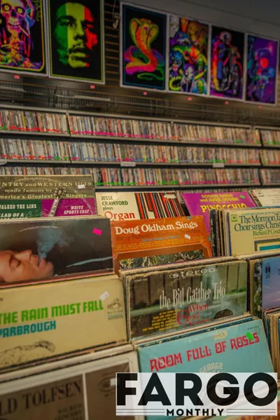 Rows of vinyl records and colorful black-light posters lining shelves in a shop