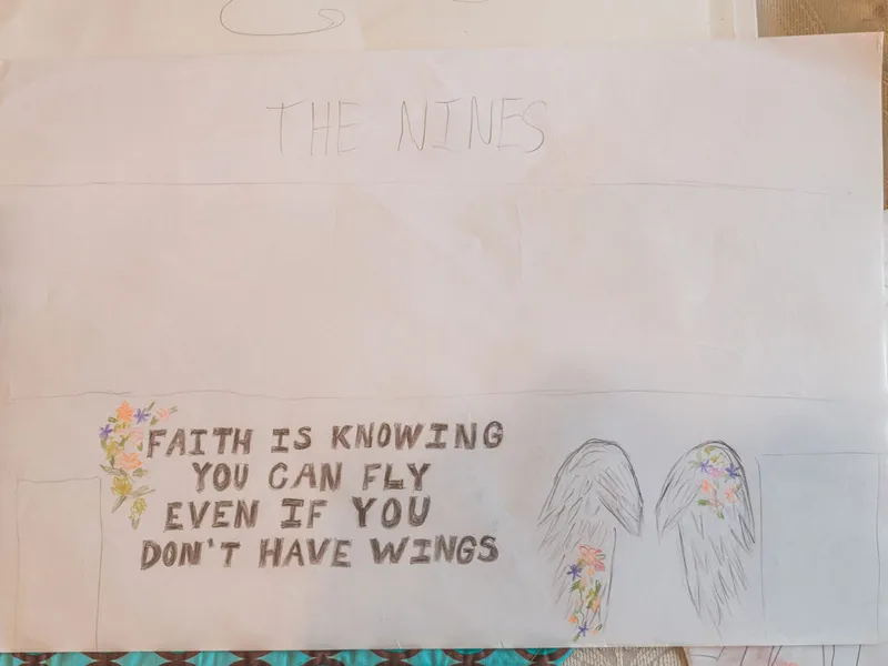 Hand-drawn sketchbook page titled 'The Nines' with pencil wings, colorful flowers, and the quote 'Faith is knowing you can