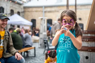 Young girl with butterfly face paint smiles at an outdoor festival