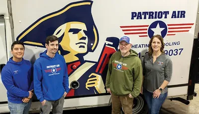 Four people smiling in front of a Patriot Air heating and cooling branded truck