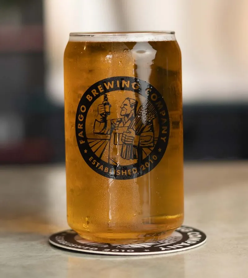 Fargo Brewing Company glass filled with golden beer resting on a branded coaster