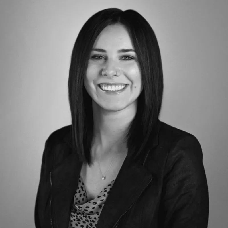 Smiling woman with straight dark hair wearing a blazer over a patterned top
