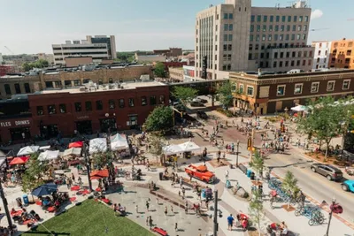 Aerial view of a busy outdoor public plaza surrounded by brick buildings and crowds of people