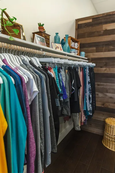 Colorful clothing hanging on double racks in a boutique with a wood-paneled accent wall