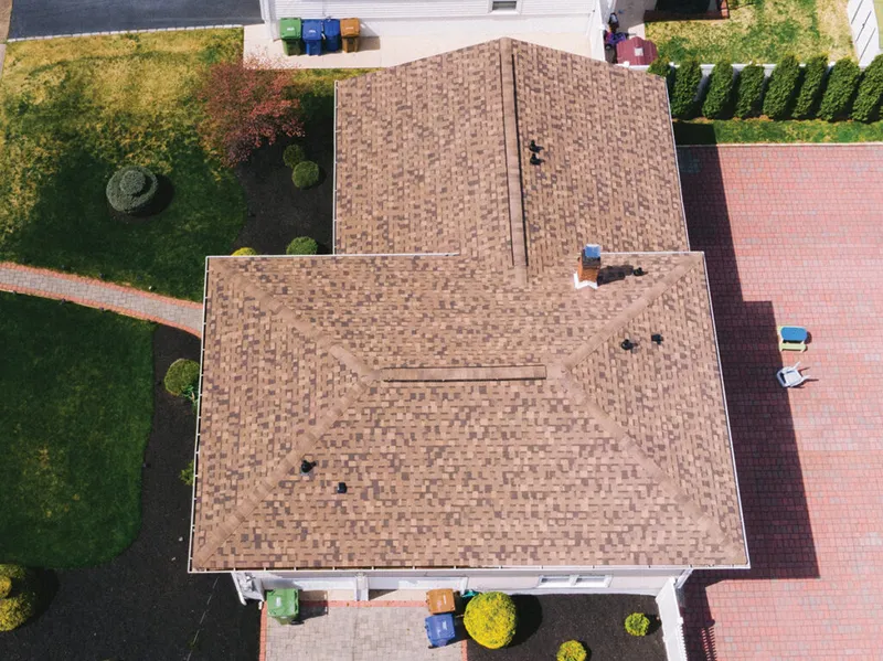 Aerial view of a suburban home with brown patterned asphalt shingle roof