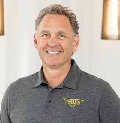 Smiling man in a gray Dabbert Custom Homes polo shirt
