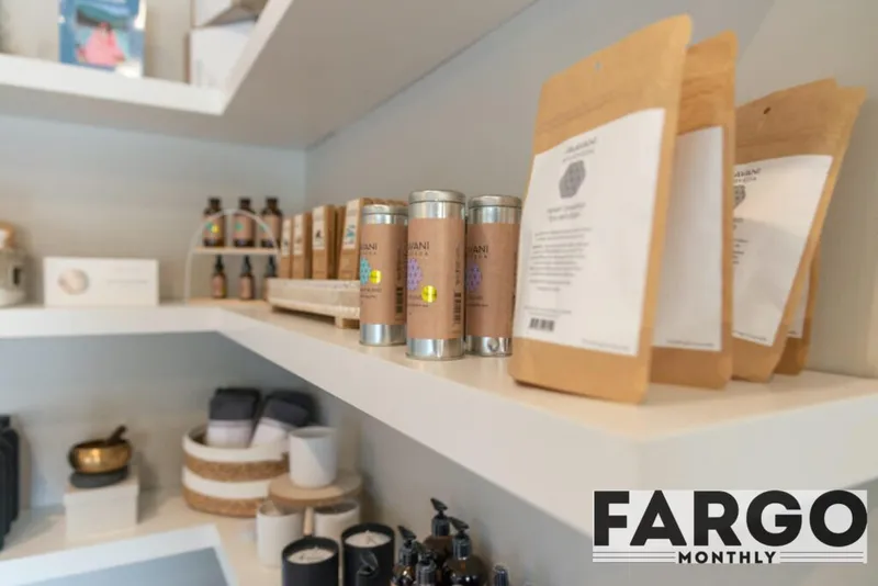 White retail shelves displaying candles, bottled products, and kraft paper pouches in a wellness shop