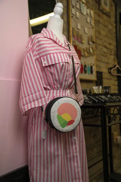 Mannequin wearing a pink-and-white striped dress with a round sushi-print crossbody bag