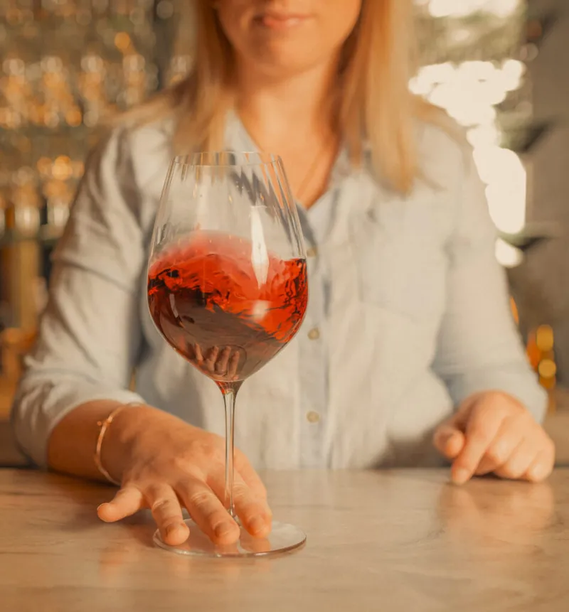 Woman swirling a glass of red wine at a marble bar