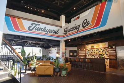 Junkyard Brewing Co. taproom with colorful striped mural, bar, and lounge seating