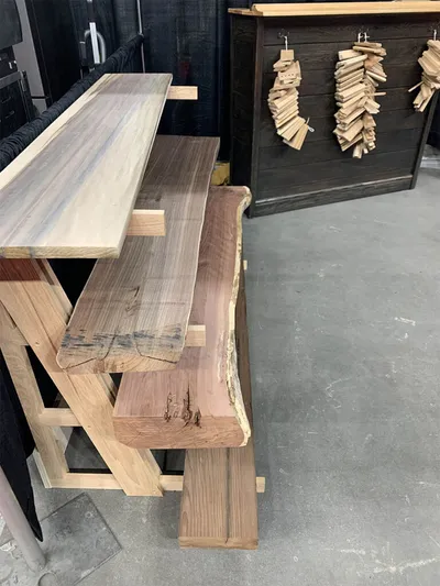 Stacked live-edge wood slabs on display stands at an indoor home show
