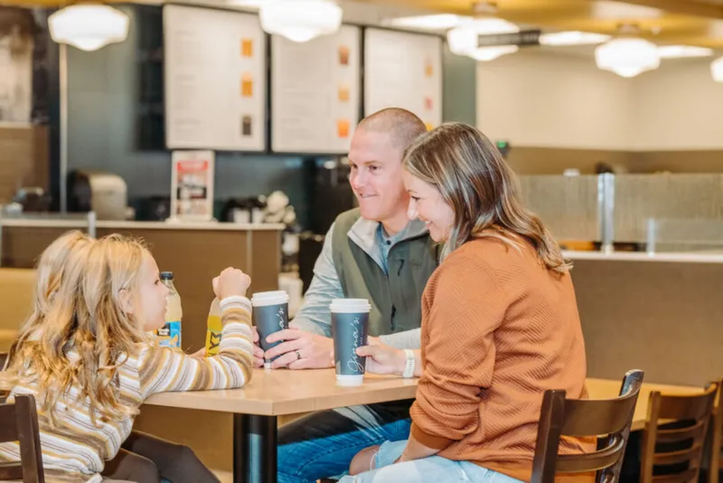 Two adults and a young girl share drinks at a casual restaurant table