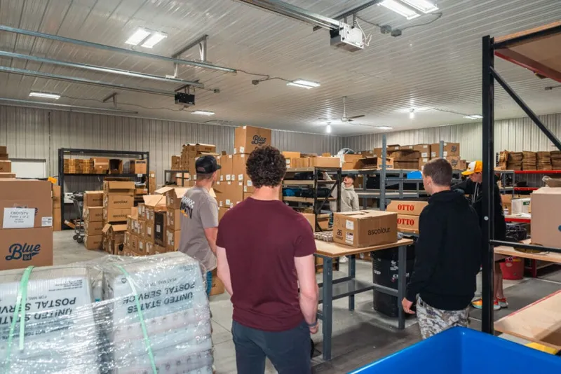 Workers sorting cardboard boxes and pallets inside a busy warehouse