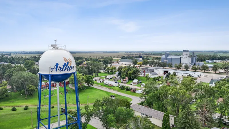Aerial view of Arthur, ND with a blue water tower labeled 'Arthur' and grain elevators beyond tree-lined streets