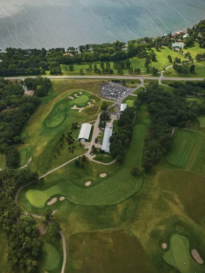 Aerial view of a golf course with sand traps and a clubhouse beside a lake