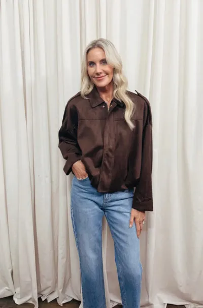 Woman with blonde hair wearing a brown button-up shirt and light-wash jeans
