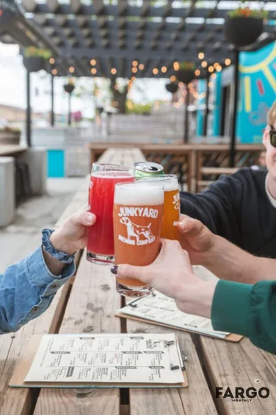 Three people toasting with craft beers on a sunny outdoor patio