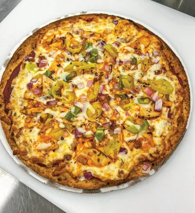 Whole pizza topped with melted cheese, red onion, green and yellow peppers, and chicken