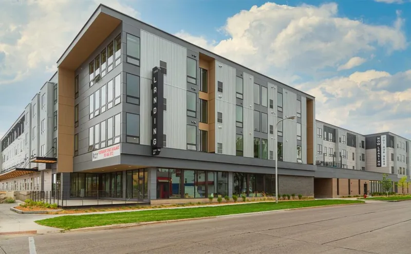 Four-story modern apartment building called The Landing with gray and tan paneling