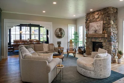 Cozy living room with a stone fireplace, curved sofa, and arched doorway to dining area