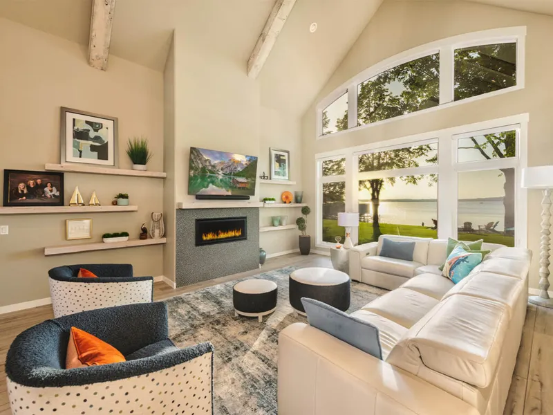 Bright living room with vaulted beamed ceiling, linear fireplace, white sectional, and large arched windows overlooking a