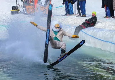 Skier splashing into an icy pond at a ski hill pond-skimming event