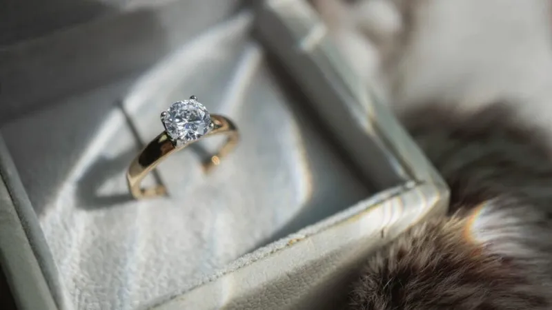 Gold solitaire engagement ring with round diamond in a velvet box